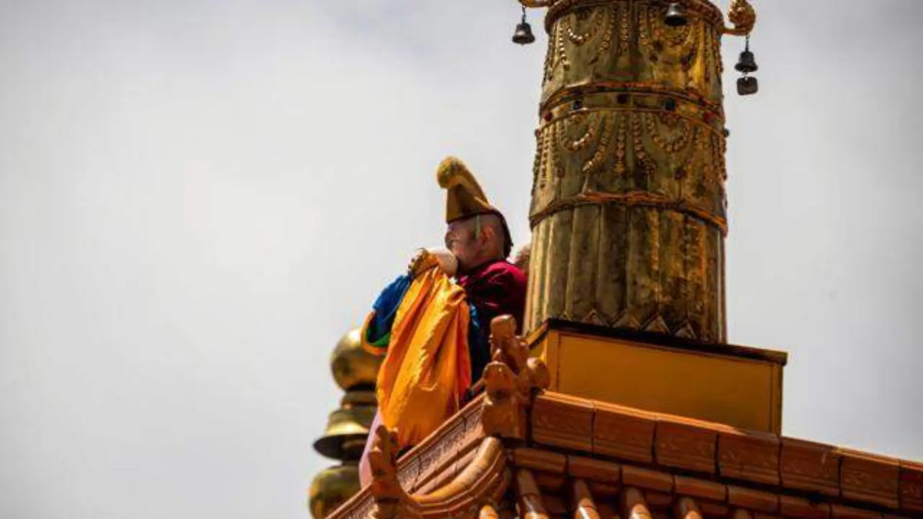 Tibetan Buddhist monk gives signal for gathering with a horn at Labrang Monastery,